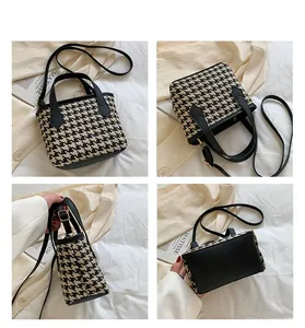 Detail view of houndstooth bucket bag showing handles, interior and leather base