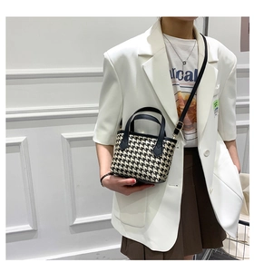 Detail of houndstooth crossbody bag with black leather handle on a stylish model