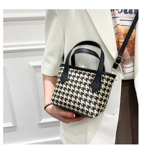 Detail of houndstooth bucket bag with leather handles and gold metal hardware accents