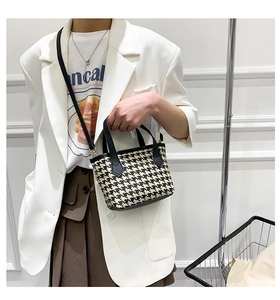 Close-up of houndstooth bucket bag with black leather handle and crossbody strap detail