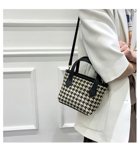 Classic houndstooth bucket bag shown on a model with black leather straps and shoulder strap