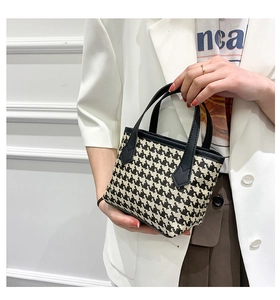 Detail of classic houndstooth tote bag with leather handles shown in a chic urban setting