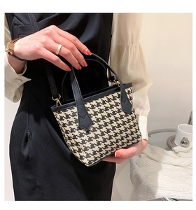 Close-up of houndstooth handbag with black faux leather handles and metal hardware