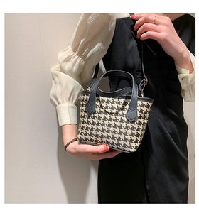 Classic houndstooth handbag with black leather handles shown on model for daily commute