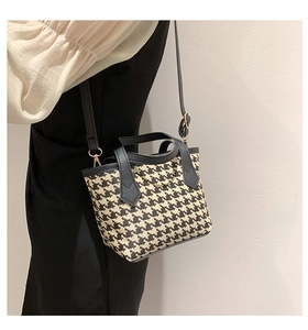 Classic black and white houndstooth bucket bag with leather handles and gold metal hardware