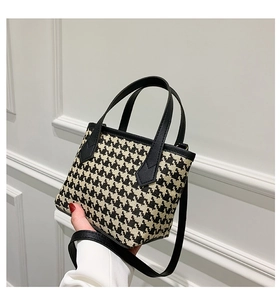 Detail of houndstooth tweed handbag with leather handles and detachable shoulder strap