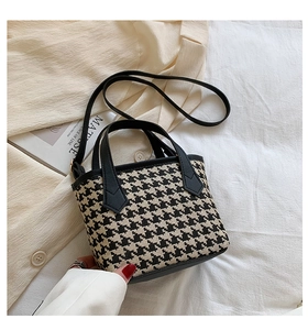 Detail of houndstooth bucket bag with black leather handle on a chic French decor background