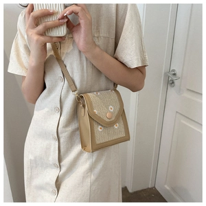 Vue détaillée du sac en paille beige avec texture de broderie de marguerites blanches