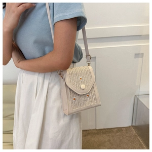 Detailed embroidery of three small daisies on a woven beige crossbody cell phone bag