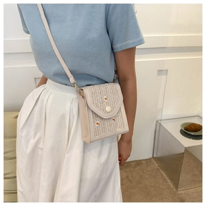 Close-up of woven straw texture and daisy embroidery on a cream mini crossbody bag