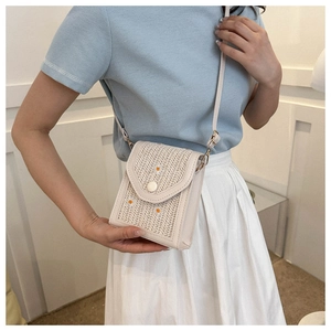 Close-up of beige woven straw crossbody bag featuring embroidered daisy flower details