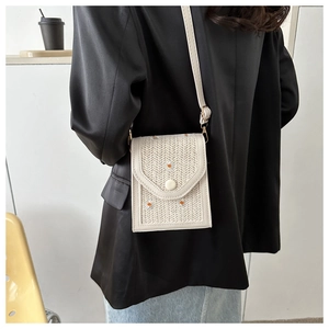Detailed view of white woven crossbody bag with daisy embroidery on model outfit
