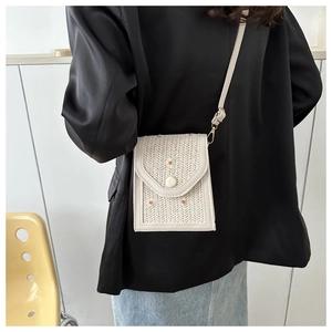 Detailed shot of a white straw woven crossbody bag with daisy embroidery on a model