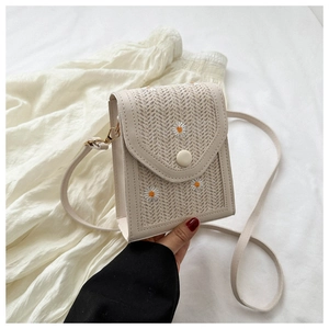 Detail of straw woven phone bag with daisy embroidery and magnetic button closure