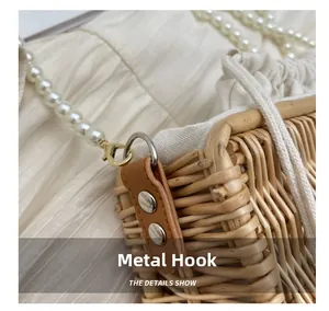 Detail of woven straw bag with pearl bead strap, metal hook, and white drawstring lining