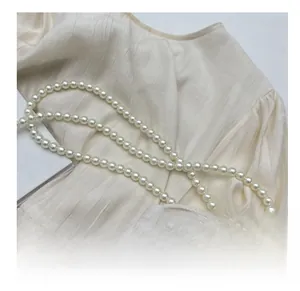 Detail of elegant pearl shoulder strap on woven rattan bag with soft texture background