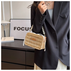 Detail of woven rattan handbag with large faux pearl handle and white drawstring closure