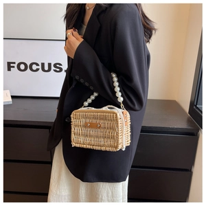Detail of hand-woven straw tote bag with elegant pearl handle and drawstring lining