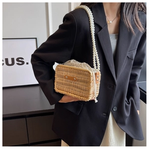 Detail of woven rattan bag featuring elegant faux pearl straps and a linen drawstring liner