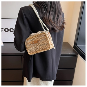 Detail of hand-woven straw bag featuring elegant pearl straps and drawstring inner bag