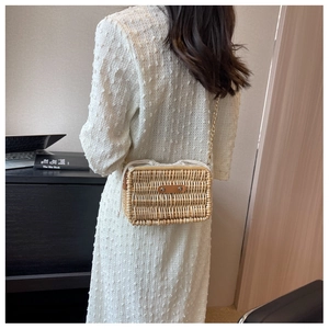 Detail of vintage woven rattan bag with leather trim and gold chain strap in use