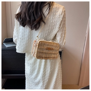 Model wearing a woven rattan shoulder bag with drawstring liner and gold chain strap
