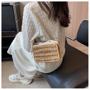 Detail of hand-woven rattan crossbody bag with leather patch and chain shoulder strap
