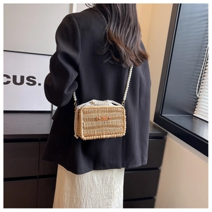 Detail of rectangular woven rattan bag featuring white pearl strap and drawstring closure