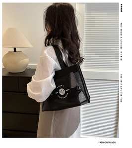 Close-up of black mesh tote bag with white circular logo and durable shoulder strap