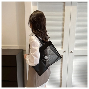 Detail view of black mesh tote bag showing the circular logo and inner zipper pouch