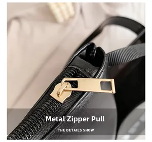 Detailed macro shot of the golden metal zipper puller on a black leather tote bag