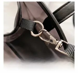 Detail of durable silver metal hook and woven strap on a black PVC tote bag