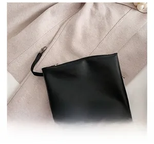 Detail view of the black portable PU leather bag with top zipper and wristlet strap