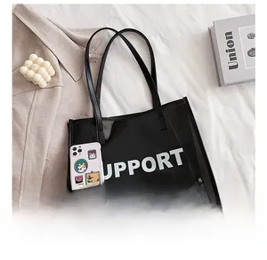 Close-up of a black transparent PVC tote bag showing large capacity compared to a phone