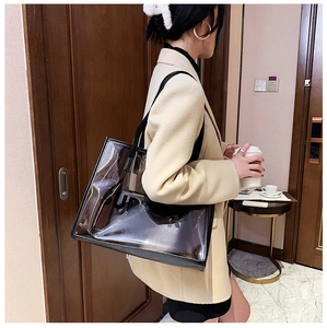 City lifestyle shot of a transparent PVC tote bag with black trim and inner pouch