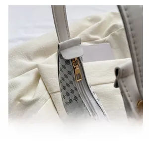 Detailansicht des glatten goldenen Reißverschlusses an der weißen Monogramm-Satteltasche