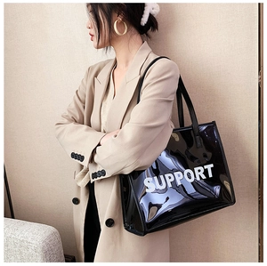 Detail of black glossy PVC tote bag featuring white SUPPORT lettering on the side