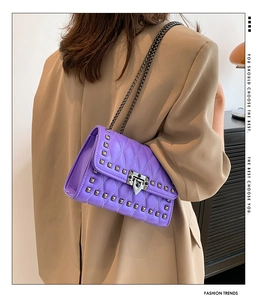 Detail of purple quilted leather crossbody bag with silver rivets and metal chain strap