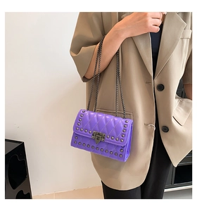 Detail view of purple quilted chain bag with studs worn by a model in casual chic style