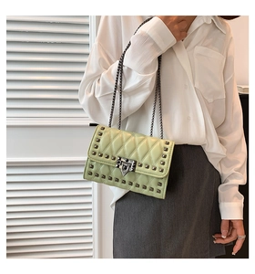 Close-up of pistachio green quilted crossbody bag with metal rivets and chain strap