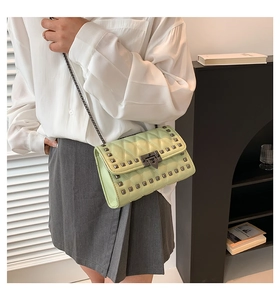 Detail of light green quilted crossbody bag with grey metallic studs and chain strap