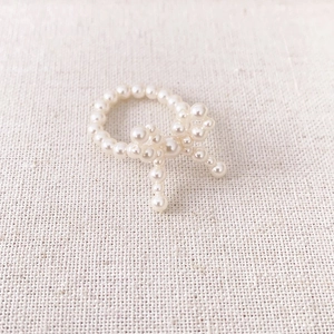 Bague élégante en perles tressées avec design de nœud sur un fond de tissu texturé