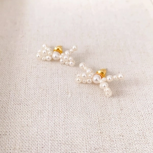 Détail macro de boucles d'oreilles nœuds en perles avec accents dorés sur tissu
