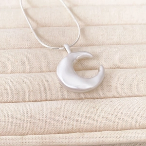 Minimalist silver crescent moon pendant necklace with brushed finish on a jewelry box