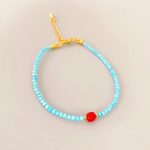 Detailed shot of blue beaded bracelet with red gemstone and gold adjustable lobster clasp