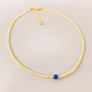Minimalist yellow beaded necklace with a blue stone centerpiece and gold lobster clasp