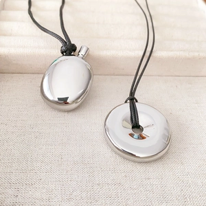 Minimalist gold-plated geometric pendants with a sleek black wax cord on a textured base