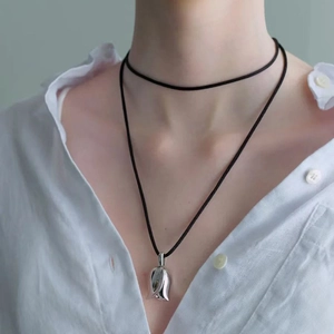 Minimalist silver tulip pendant necklace with elegant black cord worn on a white shirt
