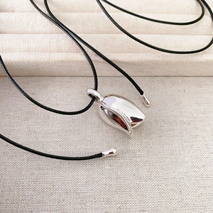 Detailed close-up of a silver tulip bud pendant on a sleek black cord necklace