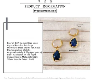 Detail view of gold-plated brass drop earrings with white crystal and blue sodalite stone